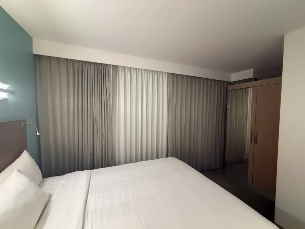 Queen bed with a flexible headboard reading light and floor-to-ceiling curtains